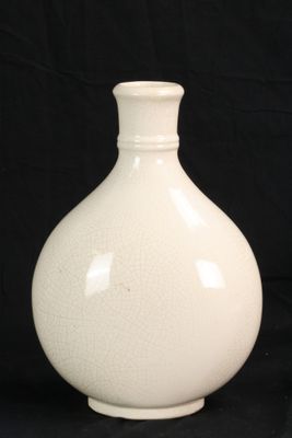 un vase blanc posé sur un fond noir
