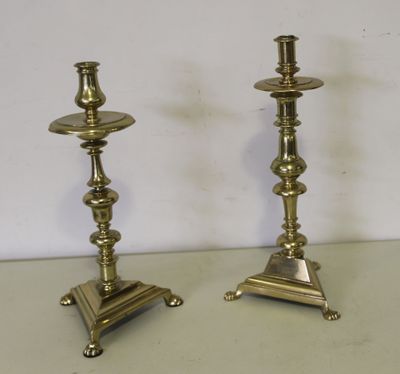 une paire de bougeoirs anciens en laiton posés sur un socle, sur une table