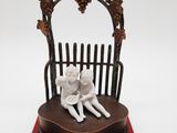 une petite figurine représentant deux enfants assis sur un banc