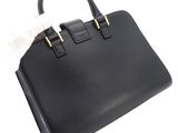 a black leather handbag with gold handles on a white background