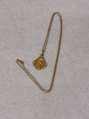 a close up of a gold necklace with a small eye on it