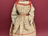 an antique doll of a woman in a dress and bonnet