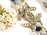 a close up of a necklace with pearls and a flower