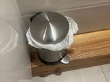 a silver pot on a wooden shelf in a bathroom