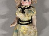 a small doll that is wearing a dress and shoes