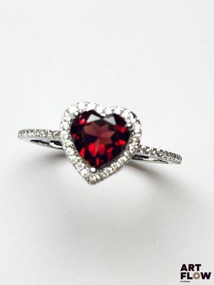une photo d'une bague ornée d'une pierre de grenat en forme de cœur, avec un anneau serti de diamants