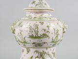 a green and white vase with a lid on a table