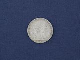 a silver coin with an image of a man and a woman on it