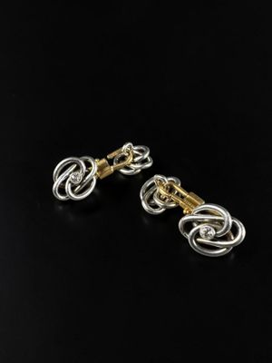 a pair of gold and silver earrings on a black background