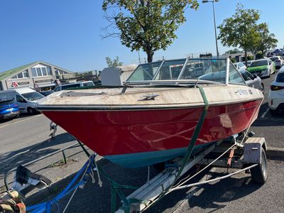 un bateau rouge et blanc sur une remorque, dans un parking