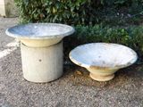 two cement bowls sitting next to each other on the ground