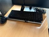 a computer keyboard and mouse on a desk with a monitor