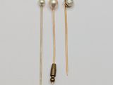 two pairs of gold and pearl ear pins on a white surface