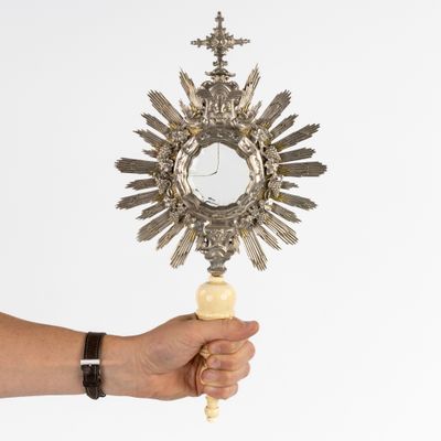 une personne tenant un miroir sur lequel est représentée une croix
