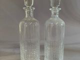 two clear glass bottles sitting on top of a table next to each other