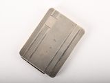 un vieux étui à cigarettes en argent posé sur une table blanche