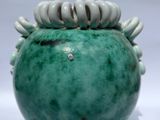 a green vase with a bunch of white beads on it