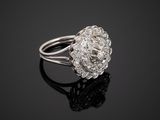 a white gold and diamond flower ring on a black surface