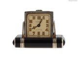 une image représentant une petite horloge en noir et blanc posée sur un socle
