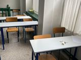 tables and chairs in an empty classroom with a window in the background
