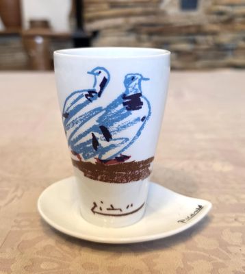 une tasse blanche ornée d'un oiseau bleu, posée sur une soucoupe