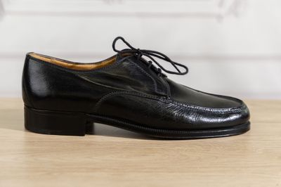 un gros plan sur une paire de chaussures noires posées sur une table en bois