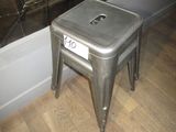 un tabouret en métal posé par terre devant un miroir
