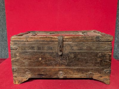 un vieux coffre en bois posé sur un tissu rouge