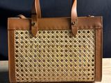 a brown and tan handbag sitting on top of a wooden table