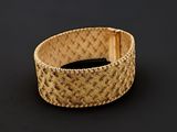 gros plan d'un bracelet en or sur une surface noire