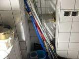 Plusieurs balais et seaux sont posés dans une salle de bains, à côté des toilettes.