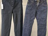 trois paires de jeans suspendues à un portant dans un magasin