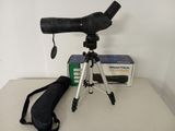 un télescope noir posé sur un trépied, à côté d'un sac noir