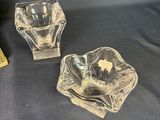 two glass ashtrays and a box of cigarettes on a blue background