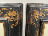 pair of black and gold framed mirrors with floral designs on them