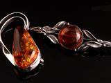 paire de boucles d'oreilles en ambre et argent, ornées de feuilles sur fond noir