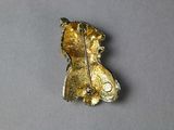 a gold brooch on a gray surface