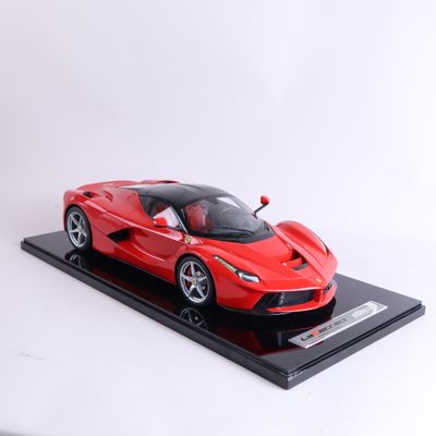 une maquette rouge d'une voiture de sport posée sur un socle noir