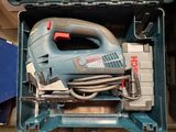 a blue box with a corded jig saw and a tool in it