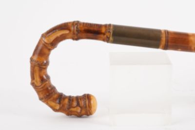 une petite pipe en bois munie d'un manche en bois, posée sur une surface blanche