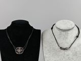 two necklaces on a mannequin stand with a black and white background