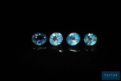 un ensemble de trois pierres précieuses de topaze bleue posées sur une surface noire