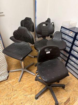 cinq chaises de bureau disposées dans une pièce, à côté d'une pile de cartons