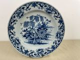 une assiette bleue et blanche décorée d'un arbre et de fleurs