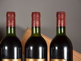 three bottles of red wine are lined up on a shelf