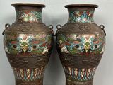 Deux vases sont posés sur un socle en bois adossé à un mur.