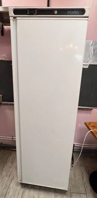 un réfrigérateur blanc dans une cuisine rose, avec un tableau noir accroché au mur