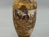 a gold vase with a painting on it sitting on a table
