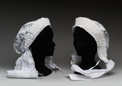 une paire de têtes de mannequin noires ornées de volants blancs et d'un bonnet blanc