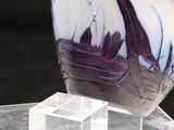a purple and white vase sitting on top of a clear cube